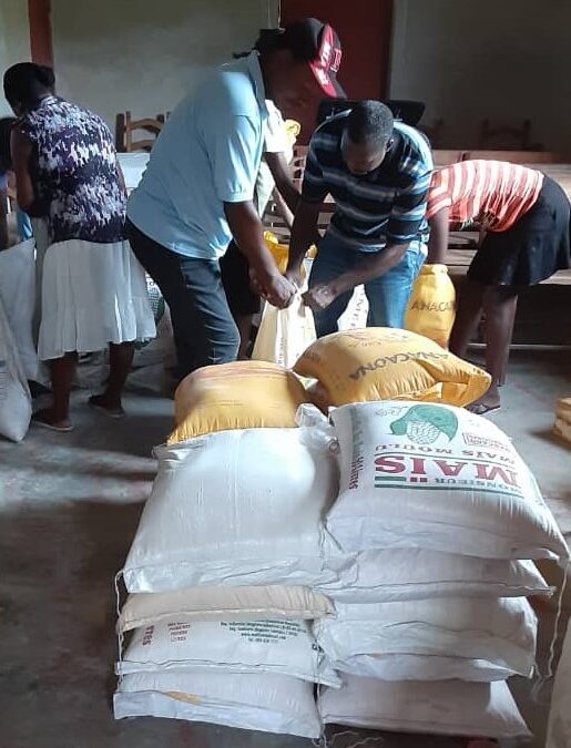 Two men moving large bags of food resources distributed to the area.
