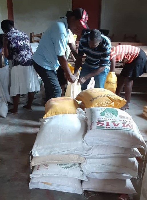 Two men moving large bags of food resources distributed to the area.